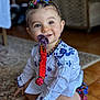 baby, child, pacifier, headband, white_shirt, blue_embroidery, floor, carpet, smiling, sitting, indoors, cute, colorful, clothing, happy, portrait, toddler, accessory, person, home