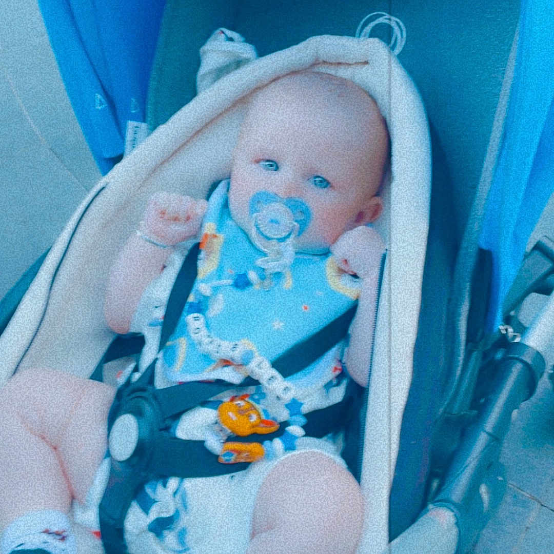 Ronnie-Lee is registered to the contest to win money with this photo: baby, baby_toy, bib, blue, child, clothing, comfort, cute, footwear, infant, outdoor, pacifier, person, portrait, relax, seatbelt, sitting, sock, stroller, young