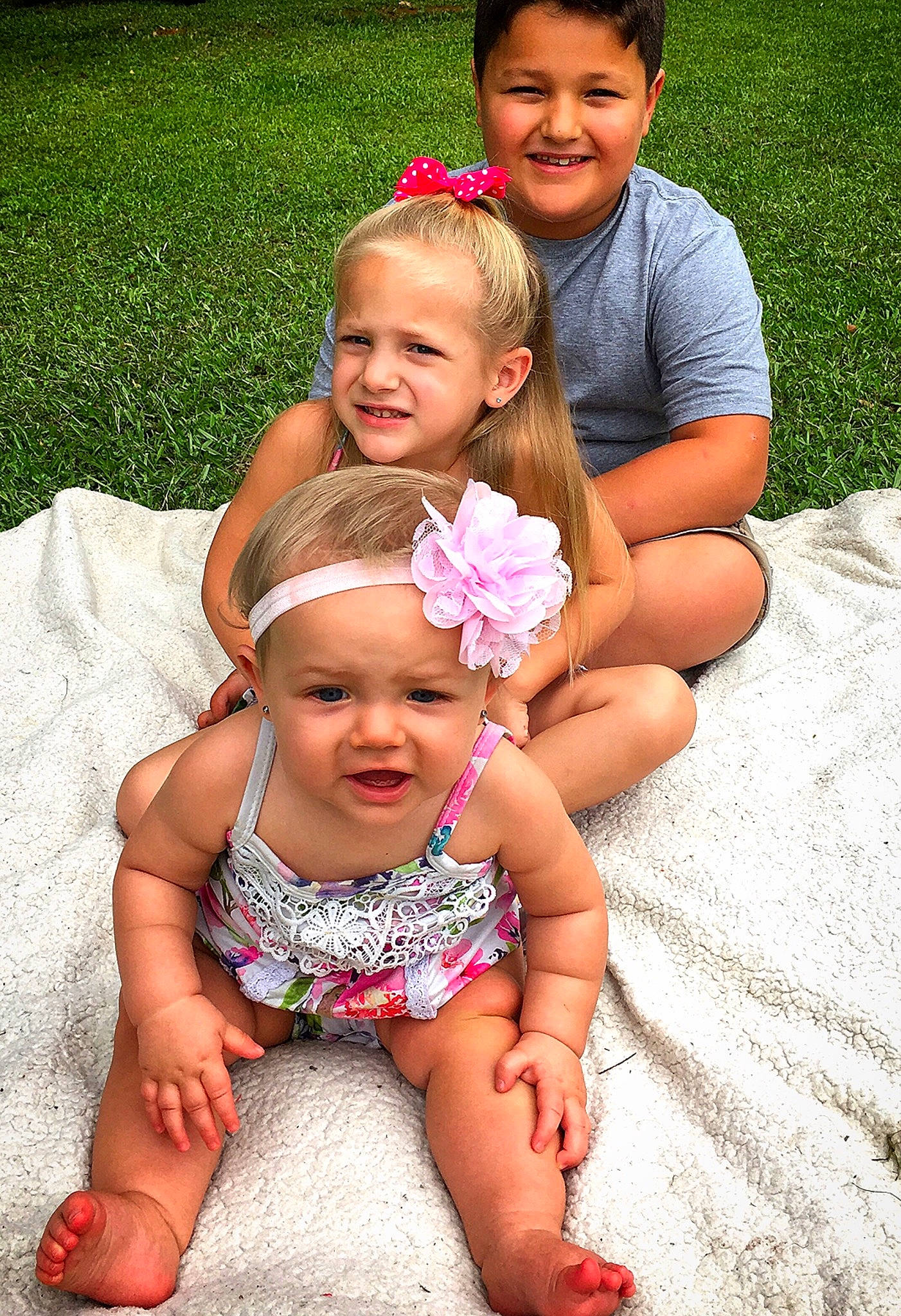 Emmalyn is registered to the contest to win money with this photo: baby, child, daughter, face, facial_expression, family, fun, grass, green, happy, interaction, joy, people, person, pink, sibling, sitting, skin, smile, summer