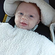 Elyo participe au concours pour gagner de l'argent avec cette photo : baby, infant, blanket, hood, smile, face, blue_eyes, car_seat, child, warm, cozy, white, fur, cute, portrait, clothing, person, soft, indoor, closeup