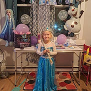 Ashlinn is registered to the contest to win money with this photo: child, birthday_party, dress, princess_costume, balloons, banner, tiara, smile, indoor, table, curtains, floor, decorations, party, frozen_theme, happy, celebration, window, toy, girl