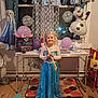child, birthday_party, dress, princess_costume, balloons, banner, tiara, smile, indoor, table, curtains, floor, decorations, party, frozen_theme, happy, celebration, window, toy, girl