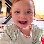 Giulia a rejoint le concours — aidez-le/la à gagner de superbes lots ! baby, infant, child, smiling, open_mouth, teeth, big_eyes, face, red_hair, green_top, onesie, clothing, indoor, home_interior, floor, table_leg, play_mat, toy, portrait, closeup