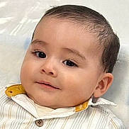 Nicolas is registered to the contest to win money with this photo: baby, child, face, smile, eyes, shirt, collar, button, lying_down, blanket, pattern, soft, comfort, portrait, cute, infant, skin, hair, young, indoors