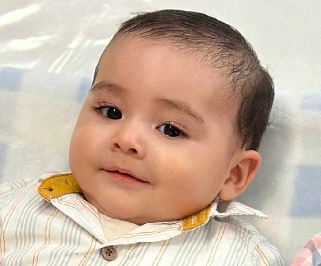 Nicolas is registered to the contest to win money with this photo: baby, child, face, smile, eyes, shirt, collar, button, lying_down, blanket, pattern, soft, comfort, portrait, cute, infant, skin, hair, young, indoors