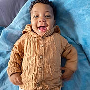 Lamine participe au concours pour gagner de l'argent avec cette photo : baby, child, smile, happy, clothing, jacket, pants, blanket, fabric, person, portrait, cute, infant, lying_down, indoors, buttoned_jacket, soft_texture, face, head, young