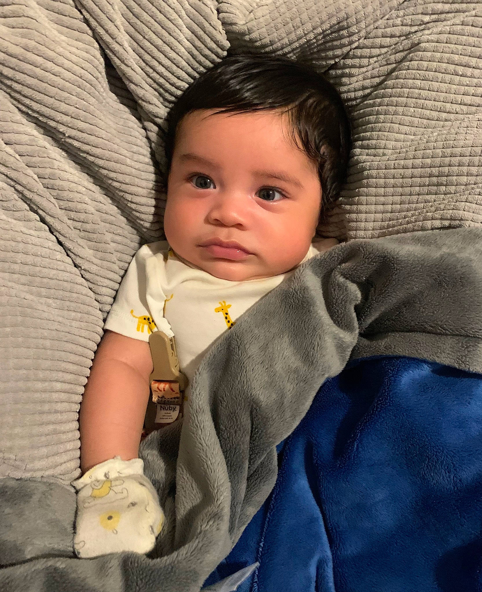 Sincere is registered to the contest to win money with this photo: baby, baby_toddler_clothing, cheek, child, comfort, eye, face, facial_expression, hairstyle, happy, human, iris, linens, nose, outerwear, person, sitting, skin, sleeve, textile