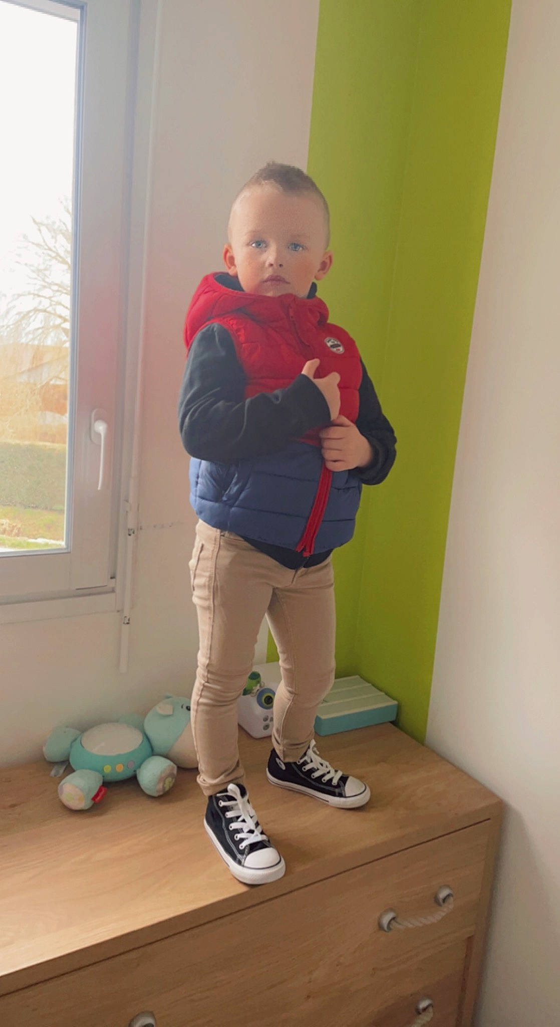 Nael participe au concours pour gagner de l'argent avec cette photo : baby, baby_toddler_clothing, child, drawer, flooring, fun, hardwood, knee, leg, person, play, room, shoe, sleeve, sneakers, sock, standing, sweatpant, toddler, window