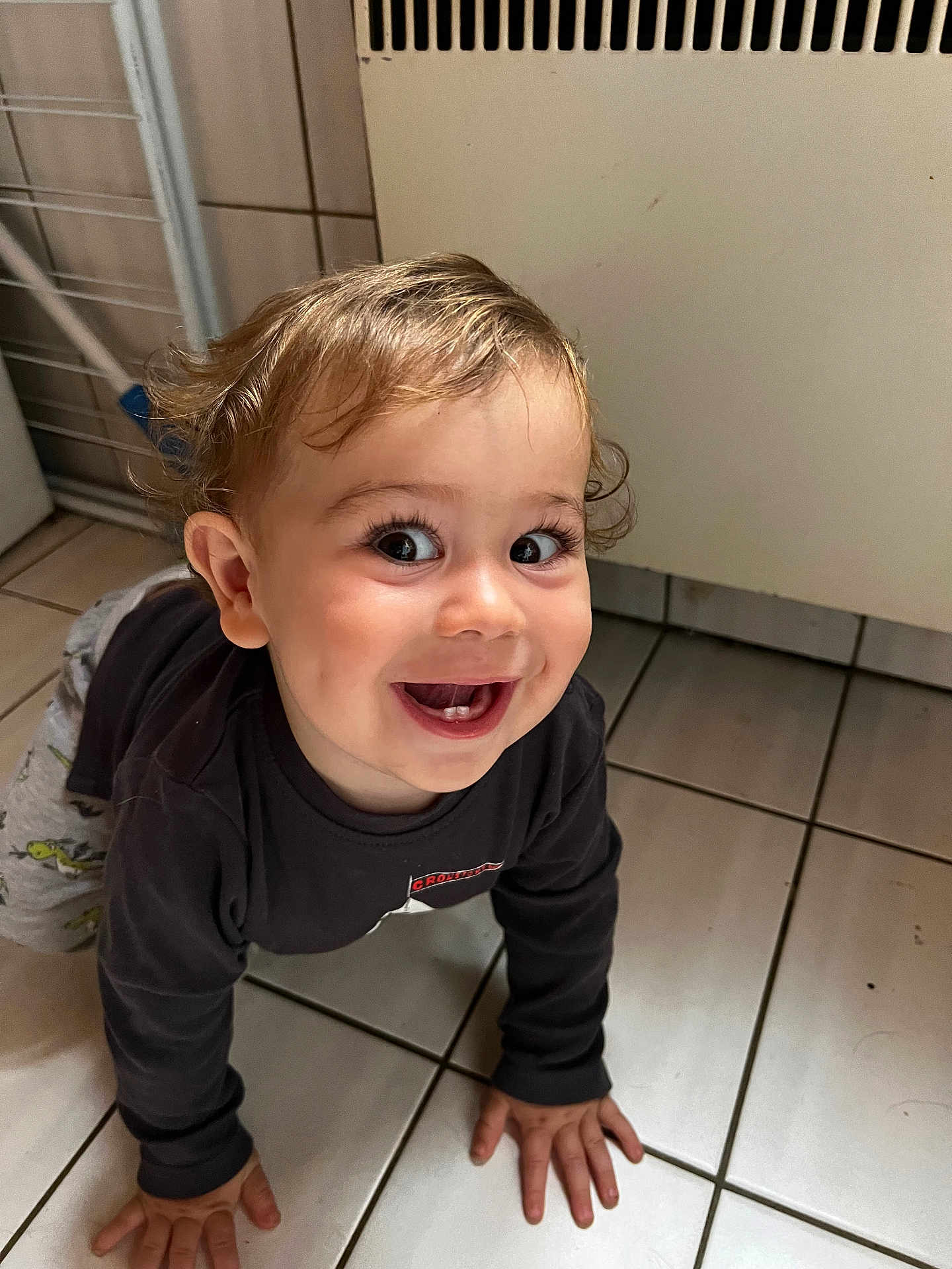 Maël participe au concours pour gagner de l'argent avec cette photo : toddler, child, crawling, smiling, happy, indoor, floor, tile, clothing, long_sleeve, pants, hair, face, expression, hands, baby, cute, person, young_child, joyful