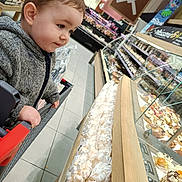 Gauthier a rejoint le concours — aidez-le/la à gagner de superbes lots ! toddler, child, shopping_cart, bakery, pastries, supermarket, food_display, glass_case, cozy_jacket, curious, indoors, floor_tiles, handrail, snack, dessert, bread, store, shopping, grocery, bakery_section