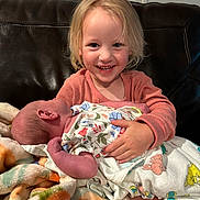 Stella is registered to the contest to win money with this photo: baby, blanket, bodypart, clothing, couch, cushion, face, finger, furniture, glove, hand, happy, head, homedecor, newborn, person, photography, portrait, quilt, smile