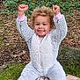 toddler, child, smiling, outdoor, forest, trees, greenery, blanket, rock, curly_hair, onesie, footwear, happy, nature, sitting, raised_hands, joyful, person, daylight, casual_clothing