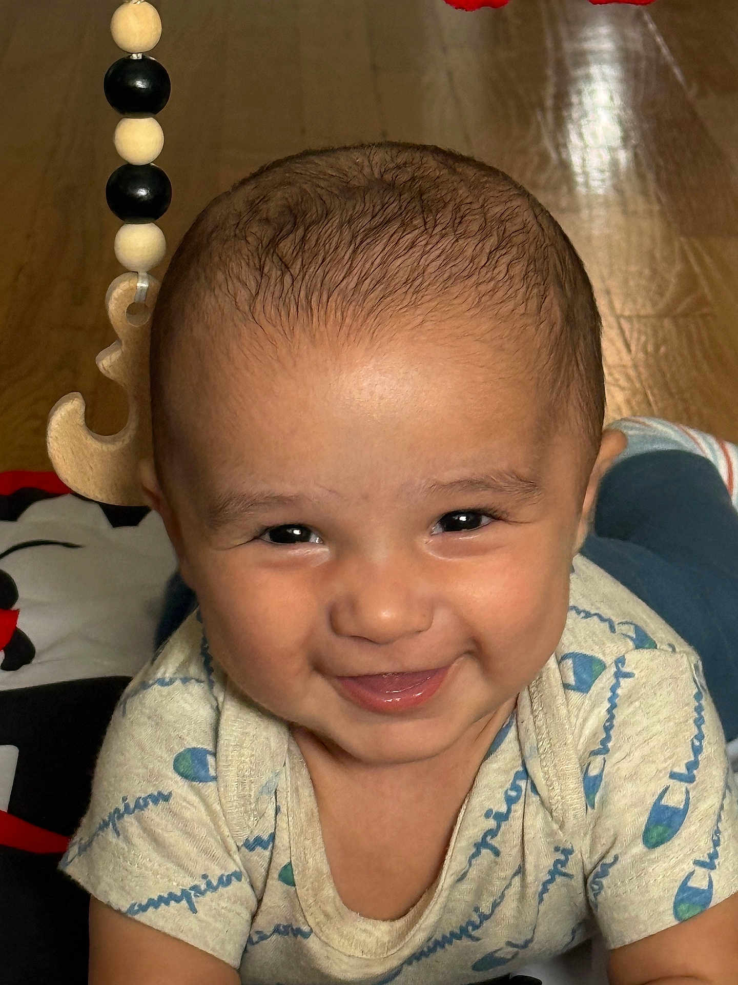 Tre joined the competition — help win amazing prizes! baby, smiling, tummy, wooden_floor, toy, wooden_beads, clothing, champion, cute, face, child, infant, happy, indoors, portrait, closeup, person, skin, head, eyes