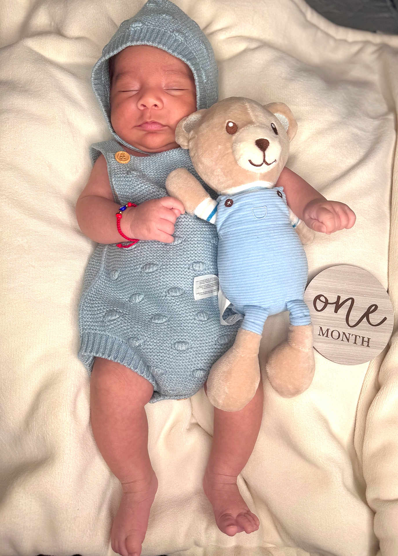 Austin is registered to the contest to win money with this photo: baby, blanket, cozy, cute, hands, hood, infant, knit_outfit, lying_down, milestone_plaque, newborn, nursery, one_month, portrait, red_bracelet, sleeping, soft_toy, stuffed_animal, teddy_bear, tiny_feet