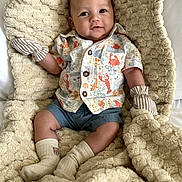 Jun is registered to the contest to win money with this photo: baby, bed, blanket, child, clothing, cozy, cute, face, happy, indoors, infant, lobster_print, photography, plush, portrait, shorts, sitting, smiling, socks, striped_mittens