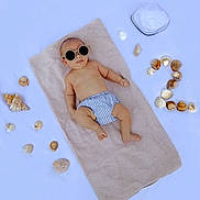 Lyzio Alias Babychou participe au concours pour gagner de l'argent avec cette photo : accessories, baby, bare_chest, beach_theme, cute, footwear_absent, hat, infant, lying_down, outdoor, portrait, relaxing, seashells, skin, small_person, striped_clothing, summer, sun_protection, sunglasses, towel