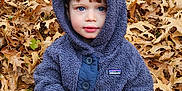 Matheo is registered to the contest to win money with this photo: child, toddler, blue_eyes, hoodie, patagonia, autumn, leaves, fall, outdoor, nature, cute, curious, sitting, cozy, clothing, portrait, seasonal, brown, orange, leaf