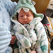 Noah is registered to the contest to win money with this photo: baby, blanket, child, clothing, cute, dinosaur, face, hand, hood, indoor, infant, person, plush, portrait, resting, sleepy, soft, toddler, wearing, wrapped