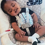 Jeremiah joined the competition — help win amazing prizes! baby, sleeping, baby_rocker, onesie, bracelet, socks, child, infant, seatbelt, pattern, comfort, resting, cute, indoors, portrait, person, peaceful, toddler, black_hair, smile