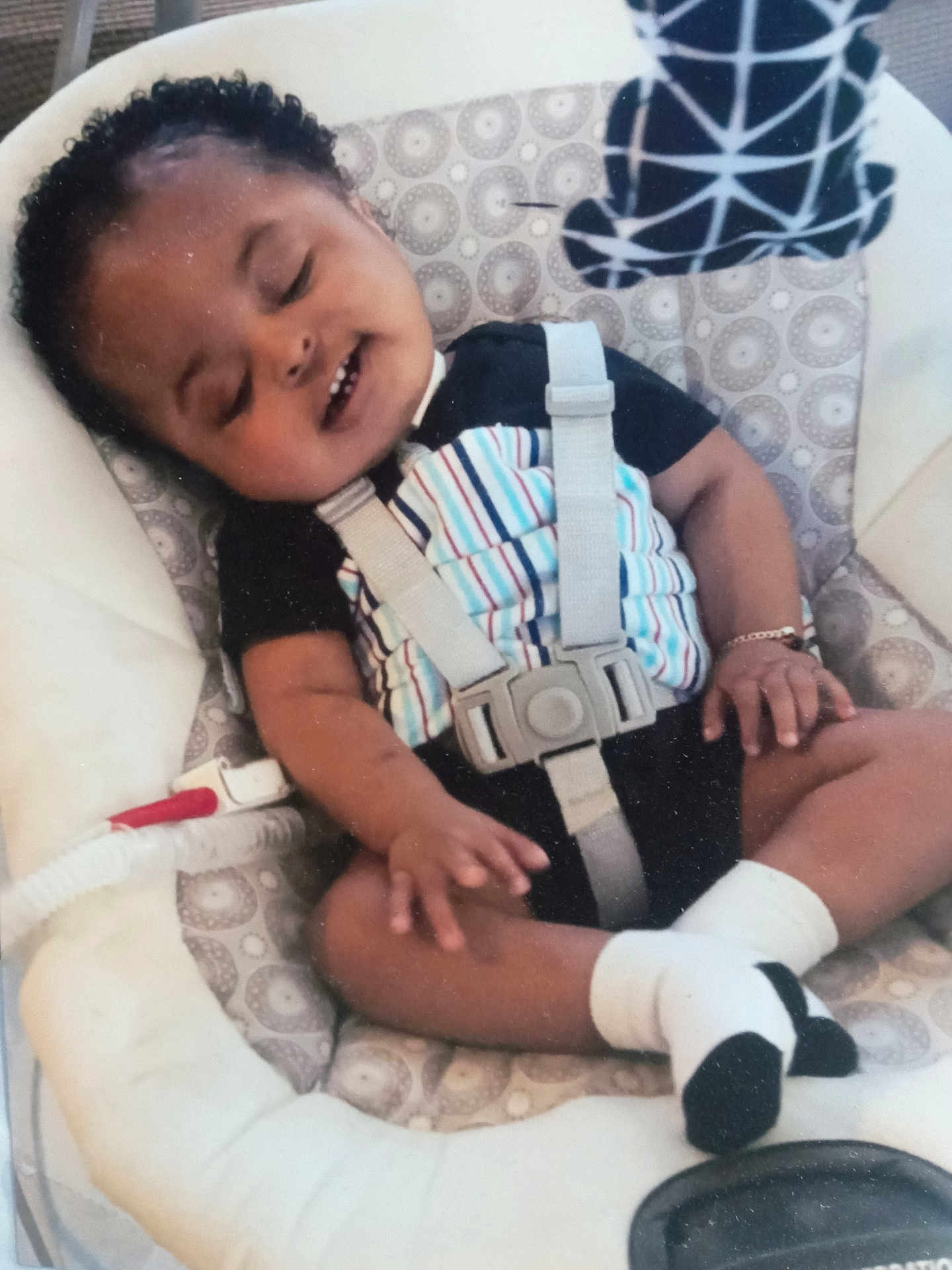 Jeremiah joined the competition — help win amazing prizes! baby, sleeping, baby_rocker, onesie, bracelet, socks, child, infant, seatbelt, pattern, comfort, resting, cute, indoors, portrait, person, peaceful, toddler, black_hair, smile