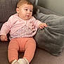 baby, child, infant, couch, pillow, pink_clothing, leggings, socks, indoor, furniture, person, cute, soft_texture, relaxed, portrait, seated, home, wall, cozy, casual