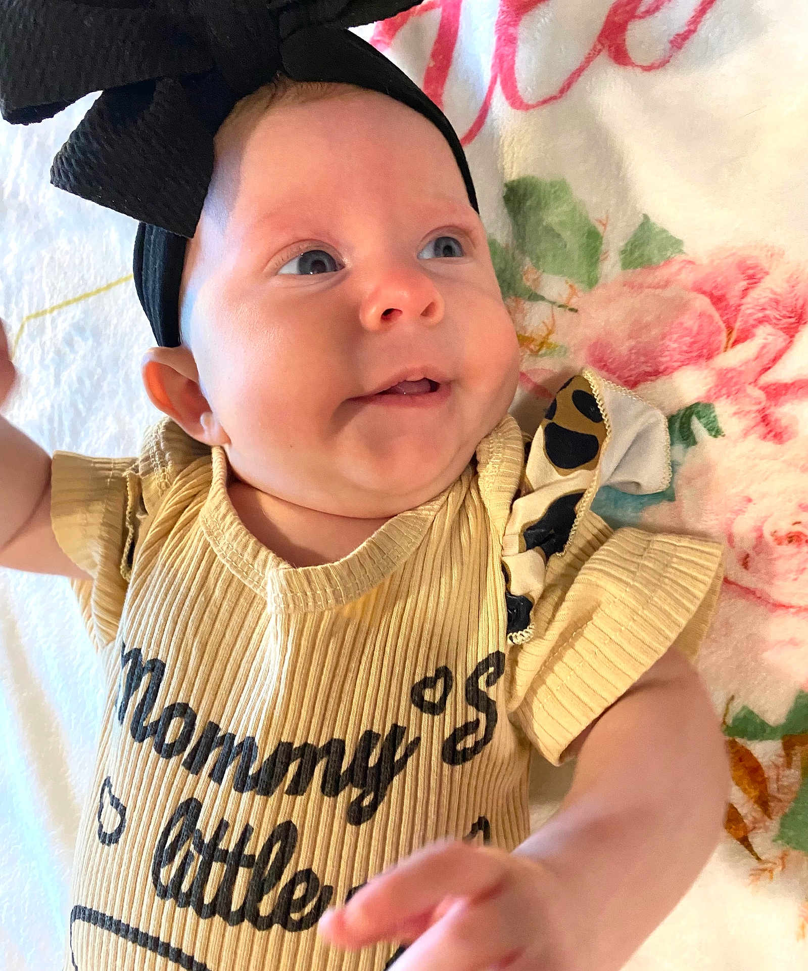 Jaycee joined the competition — help win amazing prizes! baby, child, headband, bow, yellow_clothing, face, smile, blue_eyes, blanket, floral_pattern, infant, cute, portrait, lying_down, small_hand, cheeks, soft_light, indoors, closeup, expression