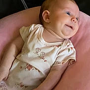 Jaycee is registered to the contest to win money with this photo: baby, infant, onesie, pink_cushion, smiling, happy, face, child, skin, portrait, indoor, person, cute, soft, resting, young, newborn, clothing, comfort, small