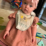 Starlite is registered to the contest to win money with this photo: baby, child, infant, pink_bow, bib, dress, carpet, toys, indoor, sitting, cute, curious, headband, footwearless, playtime, home, person, young_child, expression, floor