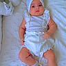 Liya is registered to the contest to win money with this photo: baby, infant, white_clothing, headwrap, socks, blanket, plush_toy, cushion, cute, indoor, portrait, soft_texture, child, lying_down, comfort, adorable, newborn, small_arms, small_legs, expression