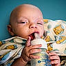 Ollie Onyx is registered to the contest to win money with this photo: baby, baby_care, blanket, blue_background, bottle, cartoon, child, close_up, drinking, eyes, face, feeding, hands, indoors, infant, lying_down, photography, portrait, swaddled, teddy_bear