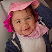 Ayla is registered to the contest to win money with this photo: toddler, child, smile, hat, pink, bib, clothing, indoor, face, person, cute, happy, jacket, baby, portrait, headwear, young_child, sitting, playful, cozy