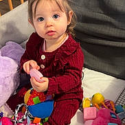 Mya participe au concours pour gagner de l'argent avec cette photo : toddler, child, baby, toys, plush_toy, colorful, couch, blanket, pigtails, curious_eyes, indoors, soft_lighting, red_clothing, socks, playing, seated, person, cute, cozy, home