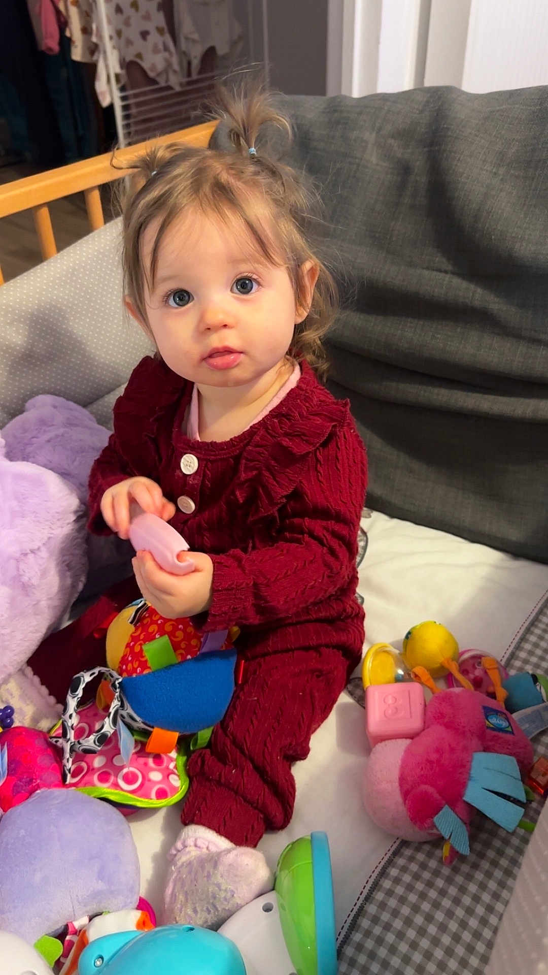 Mya participe au concours pour gagner de l'argent avec cette photo : toddler, child, baby, toys, plush_toy, colorful, couch, blanket, pigtails, curious_eyes, indoors, soft_lighting, red_clothing, socks, playing, seated, person, cute, cozy, home