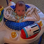 Jasper is registered to the contest to win money with this photo: activity_center, baby, blanket, carpet, child, clothing, colorful, comfort, face, floor, footwear, home, indoor, infant, person, play, seat, sneakers, soft, toy