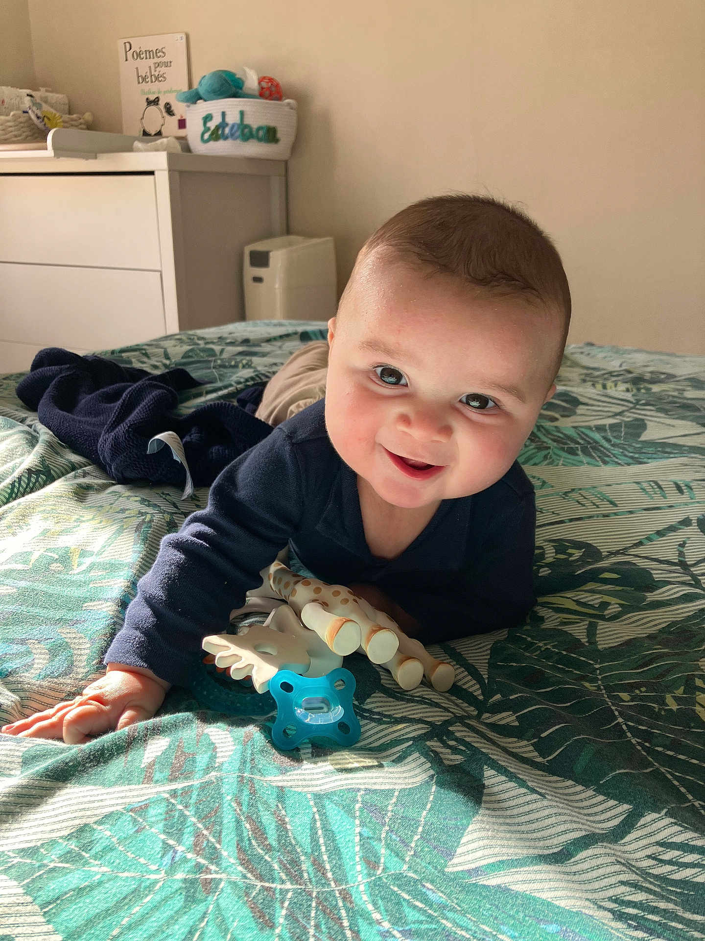 Esteban participe au concours pour gagner de l'argent avec cette photo : baby, infant, smiling, pacifier, toy_giraffe, toy, bed, blanket, leaf_pattern, nursery, dresser, basket, book, sunlight, portrait, happy, face, clothing, lying, playtime