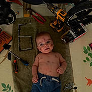 Raphaël a rejoint le concours — aidez-le/la à gagner de superbes lots ! baby, child, denim_pants, drill, expression, face, floor_mat, handyman, indoor, laying_down, messy, nails, number_six, person, playful, pliers, screwdriver, screws, tools, towel
