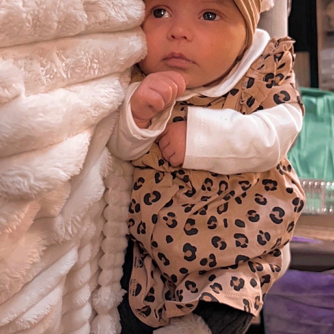 Maéna participe au concours pour gagner de l'argent avec cette photo : baby, blanket, bodypart, bonnet, cap, clothing, costume, couch, face, finger, footwear, furniture, hand, hat, head, newborn, person, photography, portrait, shoe