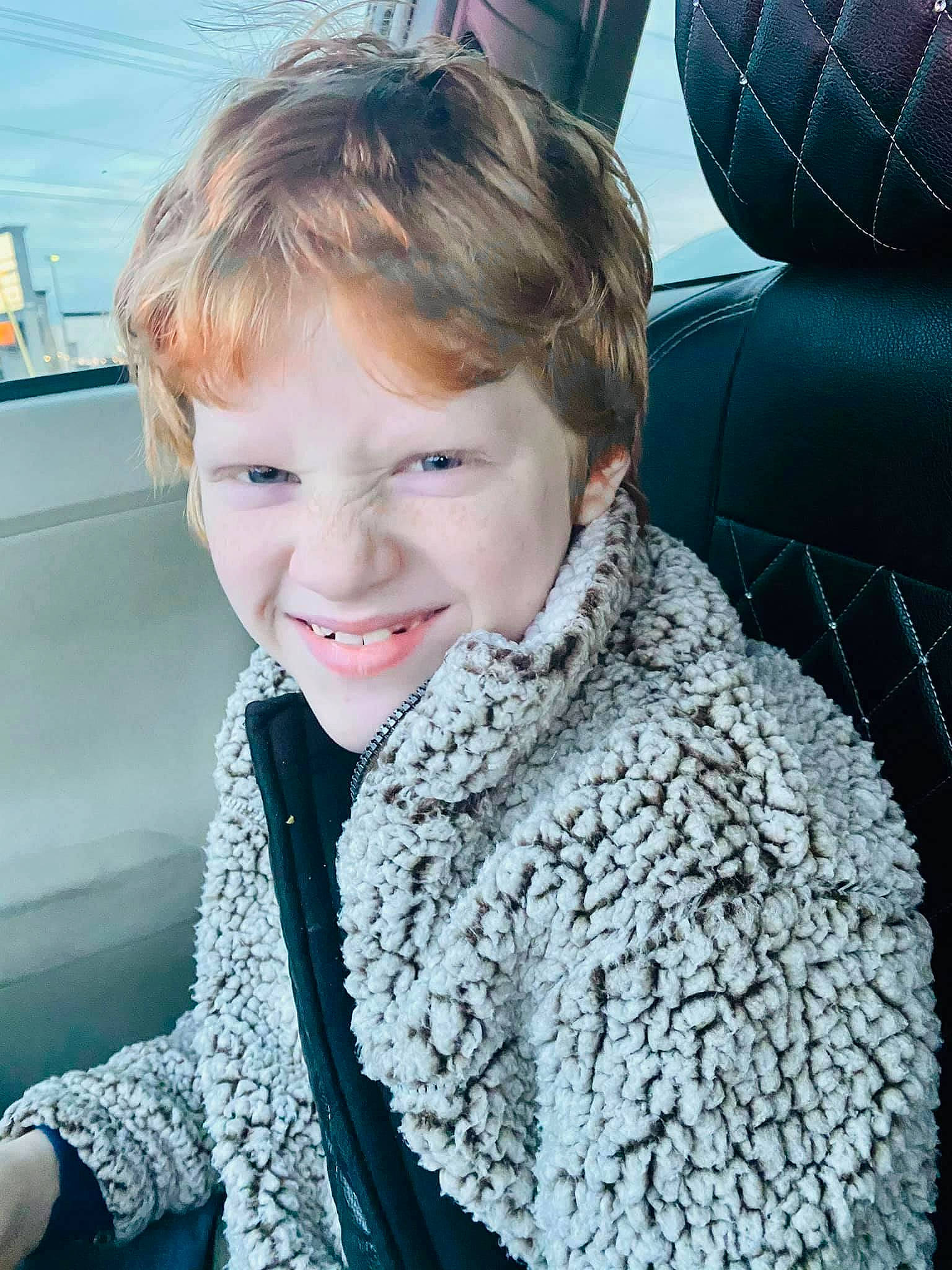 Anthony is registered to the contest to win money with this photo: child, cool, electric_blue, face, facial_expression, family_car, fashion_accessory, fun, fur, happy, human, joy, leisure, luxury_vehicle, pattern, person, sitting, skin, sleeve, smile