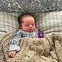 newborn, baby, sleeping, blanket, knit, onesie, leopard_print, pillow, pattern, cozy, indoor, child, resting, face, hand, cute, peaceful, infant, portrait, soft