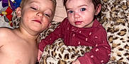 Aleah is registered to the contest to win money with this photo: child, baby, blanket, leopard_print, plush_toys, shirtless, maroon_clothing, bedroom, cute, indoor, siblings, resting, portrait, face, blue_eyes, hair, hand, wall, soft_texture, comfort