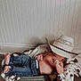 Stetson is registered to the contest to win money with this photo: baby, child, jeans, cowboy_hat, blanket, basket, floor, indoor, wood_floor, wall_paneling, relaxed, bare_chest, foot, hand, hat, cute, resting, infant, cozy, casual