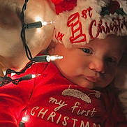 Stetson is registered to the contest to win money with this photo: baby, infant, christmas, holiday, festive, red_clothing, santa_hat, lights, indoors, cute, sleepwear, celebration, newborn, child, face, portrait, holiday_season, warm_lighting, cozy, christmas_lights