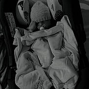 Micah is registered to the contest to win money with this photo: baby, blanket, car_seat, knitted_hat, pacifier, sleeping, indoors, cozy, infant, child, soft_texture, warm_clothing, monochrome, quiet, peaceful, resting, cushion, fabric, portrait, newborn