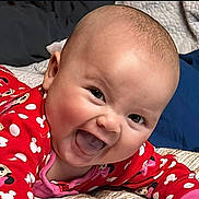 Ocean is registered to the contest to win money with this photo: baby, infant, smiling, laughing, tongue_out, close_up, portrait, pajama, red_clothing, polka_dot, minnie_mouse, bed, blanket, playful, happy, adorable, chubby_cheeks, skin, eyes, bedding