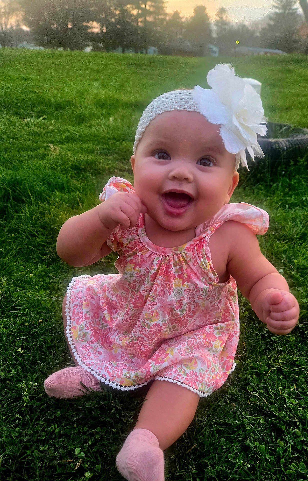 Ocean joined the competition — help win amazing prizes! baby, infant, smiling, outdoors, grass, floral_dress, headband, flower, cute, cheeks, portrait, sitting, pink_socks, happy, eyes, open_mouth, sunset, greenery, young_child, playful