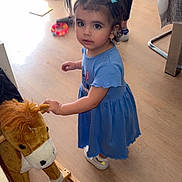 Yasmine Pinheiro a rejoint le concours — aidez-le/la à gagner de superbes lots ! blue_dress, casual_clothing, child, curious, floor, furniture, hair_ties, indoor, looking_up, person, pigtails, playroom, rocking_horse, soft_toy, standing, toddler, toy, white_shoes, wooden_floor, young_girl