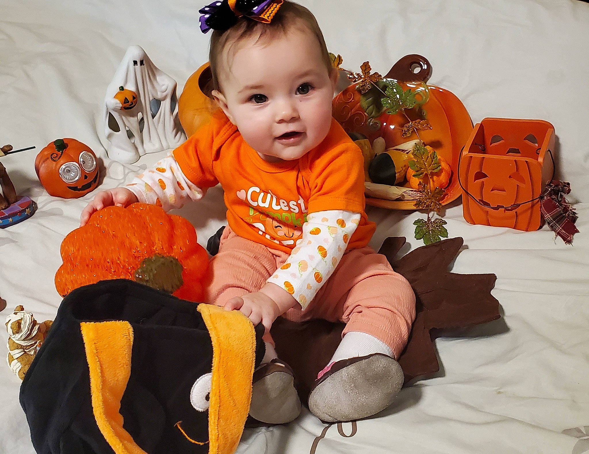 Naomi is registered to the contest to win money with this photo: arm, baby, baby_toddler_clothing, child, comfort, event, eye, face, flooring, fun, happy, head, orange, person, pumpkin, room, sitting, sleeve, t_shirt, textile