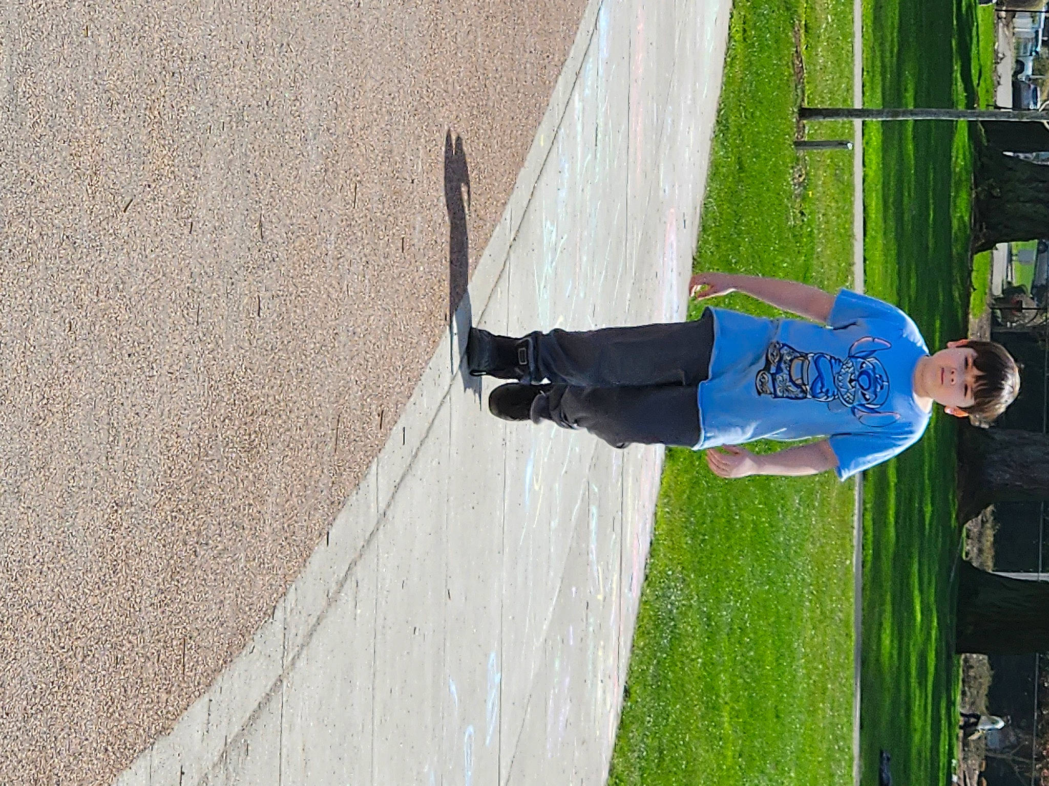 Aiden is registered to the contest to win money with this photo: asphalt, concrete, denim, electric_blue, fun, grass, knee, leisure, outdoor_shoe, person, recreation, road_surface, shadow, sidewalk, smile, sports, walking_shoe
