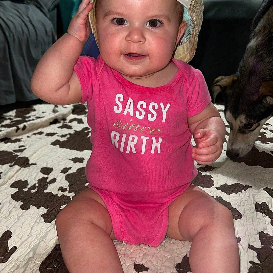 Charlee joined the competition — help win amazing prizes! baby, baseballcap, bed, bedroom, cap, clothing, couch, cushion, face, furniture, hat, head, homedecor, indoors, person, photography, portrait, room, sitting, t_shirt
