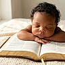 Khrome is registered to the contest to win money with this photo: baby, infant, sleeping, book, open_book, reading, bed, blanket, indoor, window, warm_light, portrait, face, curly_hair, peaceful, resting, close_up, home, cozy, photography